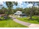 Two-story home with a screened-in pool, surrounded by lush greenery and a winding driveway at 4949 Lake Kotsa Dr, Lake Wales, FL 33898