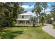Charming two-story home with a metal roof, inviting front porch, and lush landscaping at 4949 Lake Kotsa Dr, Lake Wales, FL 33898