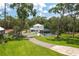 Two-story home with a screened-in pool, surrounded by lush greenery and a winding driveway at 4949 Lake Kotsa Dr, Lake Wales, FL 33898