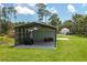 Large metal garage and carport with a vehicle and lawn equipment stored on a grassy lot at 4949 Lake Kotsa Dr, Lake Wales, FL 33898