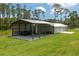 Large metal garage and carport with a vehicle and lawn equipment stored on a grassy lot at 4949 Lake Kotsa Dr, Lake Wales, FL 33898
