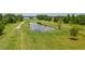 Aerial view of a serene pond reflecting the sky, surrounded by lush green fields at 4949 Lake Kotsa Dr, Lake Wales, FL 33898