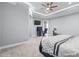 Spacious bedroom featuring a tray ceiling, ceiling fan, ensuite access, and light gray walls and flooring at 607 S 16Th St, Haines City, FL 33844