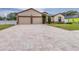 Inviting home featuring a two-car garage, neutral paint, stone accents, and a long, patterned paver driveway at 607 S 16Th St, Haines City, FL 33844