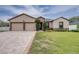 Inviting home featuring a two-car garage, neutral paint, stone accents, and a long, patterned paver driveway at 607 S 16Th St, Haines City, FL 33844