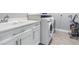 Well-lit laundry room featuring front-load washer, dryer, sink, white cabinetry, and light gray flooring at 607 S 16Th St, Haines City, FL 33844