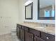 A bathroom features a double sink vanity with granite countertops, matching cabinets, and framed mirrors at 830 Cabaret Ct, Kissimmee, FL 34759
