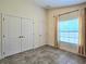 An empty bedroom with a window, closet, and neutral colored tile flooring at 830 Cabaret Ct, Kissimmee, FL 34759