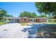 Charming brick home featuring a covered carport, mature trees, and a welcoming driveway at 961 Oleander Se Dr, Winter Haven, FL 33880