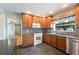 Cozy kitchen featuring warm wood cabinetry, mosaic backsplash, and stainless steel dishwasher at 961 Oleander Se Dr, Winter Haven, FL 33880