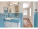 Classic blue bathroom showcasing tiled walls, vanity with sink and a view of the bedroom at 961 Piedmont Se Dr, Winter Haven, FL 33880
