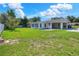 Expansive yard featuring green grass, mature trees, and connected Florida room and carport at 961 Piedmont Se Dr, Winter Haven, FL 33880
