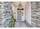 Front door with security screen, stone columns, hanging light fixture, and fresh landscaping at 114 Belmont Dr, Winter Haven, FL 33884