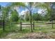 Fenced backyard area with metal gate surrounded by greenery, offering privacy and a clear property boundary at 1273 Scrub Jay Trl, Frostproof, FL 33843