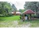 Lush backyard with a well house and a glimpse of the home, surrounded by greenery and a well-manicured lawn at 1273 Scrub Jay Trl, Frostproof, FL 33843