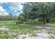 Expansive, grassy backyard with a wooden fence, mature trees, and partial sandy areas, offering a vast outdoor space at 1273 Scrub Jay Trl, Frostproof, FL 33843