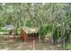 A charming chicken coop sits amidst trees draped with Spanish moss, creating a picturesque rural scene at 1273 Scrub Jay Trl, Frostproof, FL 33843