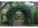 Whimsical garden gate covered in lush greenery, leading to a tranquil outdoor space at 1273 Scrub Jay Trl, Frostproof, FL 33843