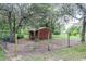 Small, fenced-in shed with a simple design, nestled among trees and greenery, providing storage in a natural setting at 1273 Scrub Jay Trl, Frostproof, FL 33843