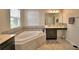 Bright bathroom featuring a bathtub, black vanity, and a large window at 1433 Bunker Dr, Davenport, FL 33896
