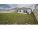 An expansive, grassy backyard features a covered patio and a tidy fence and landscaping at 1719 Durden Dr, Winter Haven, FL 33880