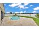 A kidney-shaped swimming pool with travertine decking surrounded by green grass at 1765 Kingsmill Dr, Bartow, FL 33830