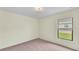 Bedroom with plush carpet, cream walls and a window overlooking outdoor greenery at 1765 Kingsmill Dr, Bartow, FL 33830