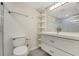 Clean bathroom features a shower, commode, shelving and a single sink vanity with drawers at 208 Lake Howard Nw Dr # 104, Winter Haven, FL 33880