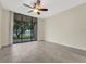 Bright bedroom with tile flooring, ceiling fan, and sliding doors leading to a balcony with views at 208 Lake Howard Nw Dr # 104, Winter Haven, FL 33880