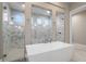 Bathroom showcasing a modern tub and glass-enclosed showers with marble tile at 209 Pine Lilly Ct, Lake Alfred, FL 33850