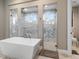 Bathroom showcasing a modern tub and glass-enclosed showers with marble tile at 209 Pine Lilly Ct, Lake Alfred, FL 33850