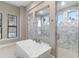 Bathroom showcasing a modern tub and glass-enclosed showers with marble tile at 209 Pine Lilly Ct, Lake Alfred, FL 33850