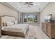 Bright bedroom with tray ceilings, ceiling fan, wood floors, and backyard views from the black trimmed window at 209 Pine Lilly Ct, Lake Alfred, FL 33850
