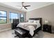 Bedroom features a dark wood framed bed, a dark ceiling fan, hardwood floors, and lots of light at 209 Pine Lilly Ct, Lake Alfred, FL 33850