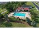 Aerial view of a community pool area with ample seating, lush landscaping, and a clubhouse, perfect for relaxation at 209 Pine Lilly Ct, Lake Alfred, FL 33850