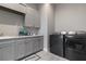 A view of the laundry room with grey cabinets, granite countertops and modern washer and dryer units at 209 Pine Lilly Ct, Lake Alfred, FL 33850