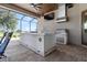 Outdoor kitchen with a built-in grill, countertop seating, and a view of the backyard and television at 209 Pine Lilly Ct, Lake Alfred, FL 33850