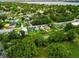 A high angle aerial view displays the property amidst a residential neighborhood and mature trees with a lake in the distance at 2480 Avenue E Sw, Winter Haven, FL 33880