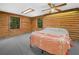 Comfortable bedroom with log walls, a ceiling fan, two windows and carpeted floor at 2530 Arbuckle Shores Rd, Frostproof, FL 33843