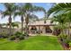 Beautiful backyard featuring a pergola, outdoor kitchen, well-manicured lawn, and mature palm trees at 2612 San Simeon Way, Kissimmee, FL 34741