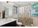 Cozy bathroom featuring a single sink vanity, shower with curtain, window, and modern fixtures at 2612 San Simeon Way, Kissimmee, FL 34741