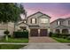 Charming two-story home featuring a brick driveway, well-manicured lawn, and red shutters at dusk at 2612 San Simeon Way, Kissimmee, FL 34741