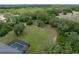 Aerial shot showcasing a large, green lot, complemented by mature trees and a partially visible pool enclosure at 3985 Mammoth Grove Rd, Lake Wales, FL 33898