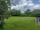 Tranquil backyard view showing a vast green lawn, mature trees, and a glimpse of the screened pool area at 3985 Mammoth Grove Rd, Lake Wales, FL 33898