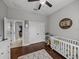 Light and airy bedroom featuring wood floors, a ceiling fan, and a white crib with KREW wall decor at 3985 Mammoth Grove Rd, Lake Wales, FL 33898