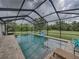 Relaxing screened-in pool with a green backyard view, basketball hoop, and tiled pool deck at 3985 Mammoth Grove Rd, Lake Wales, FL 33898