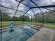 Screened-in pool area with lounge chairs, basketball hoop, and views of the green backyard at 3985 Mammoth Grove Rd, Lake Wales, FL 33898