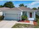 Charming single-story home featuring an attached two-car garage, red door, landscaped front yard, and mature trees at 481 Kensington View Dr, Winter Haven, FL 33880