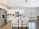 Bright kitchen features white cabinets, stainless steel appliances, and a center island with bar seating at 481 Kensington View Dr, Winter Haven, FL 33880