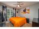 Comfortable bedroom with ceiling fan, neutral walls, and bright orange comforter at 536 Squires Grove Dr, Winter Haven, FL 33880